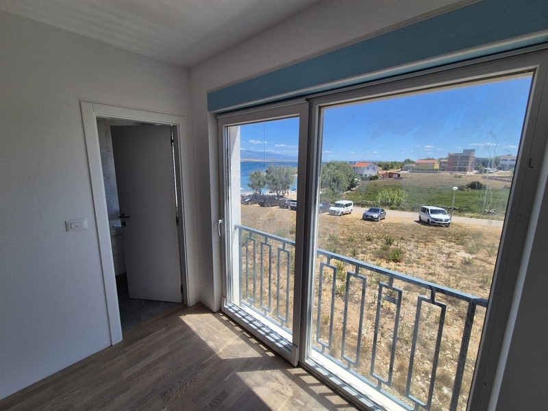 Chambre avec grandes fenêtres et accès à un balcon avec vue mer.