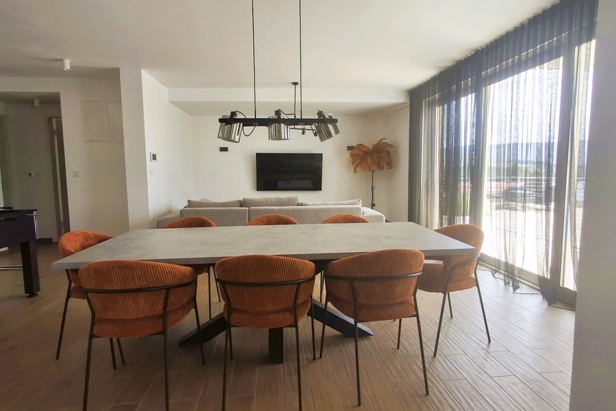 Coin repas clair avec grandes baies vitrées et vue mer