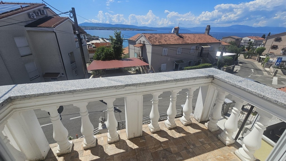Balcon avec balustrade en pierre et vue sur les toits et la mer
