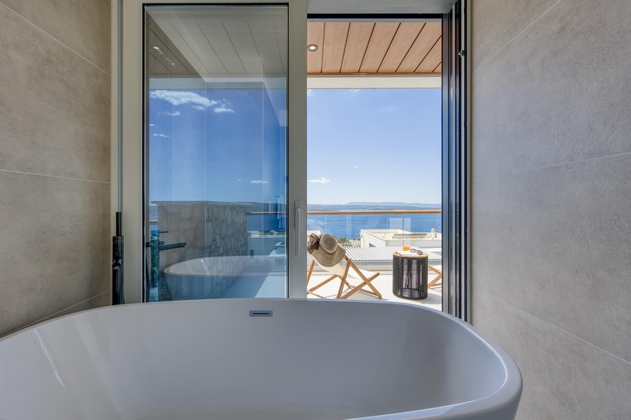 Salle de bains avec baignoire îlot et vue mer