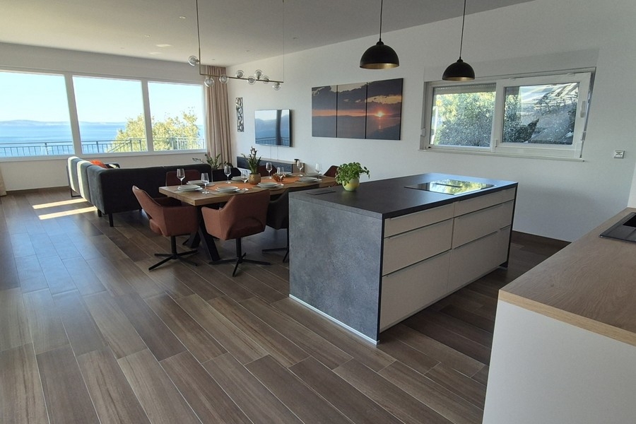 Cuisine-salle à manger avec îlot, table à manger et canapé devant des fenêtres panoramiques