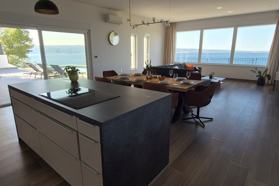 Îlot de cuisine avec table à manger et vue mer depuis la terrasse