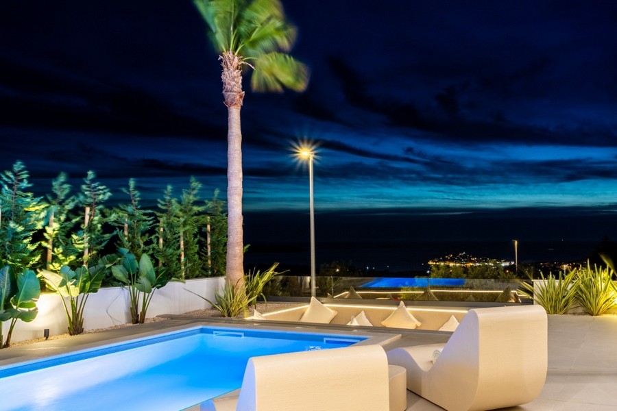 Espace piscine éclairé de nuit avec vue mer