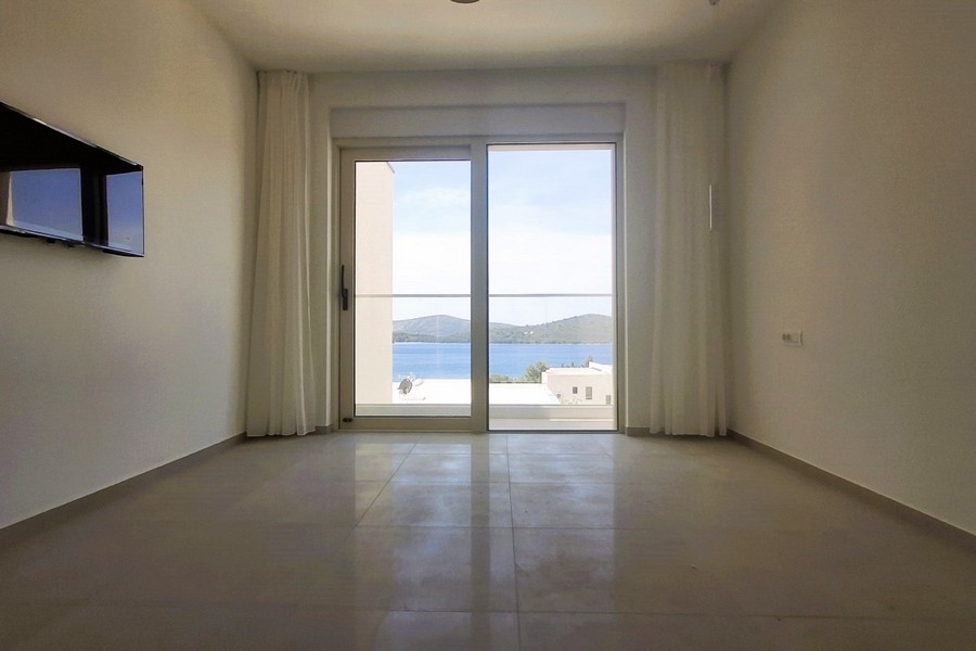 Pièce avec téléviseur mural et vue mer à travers la porte vitrée