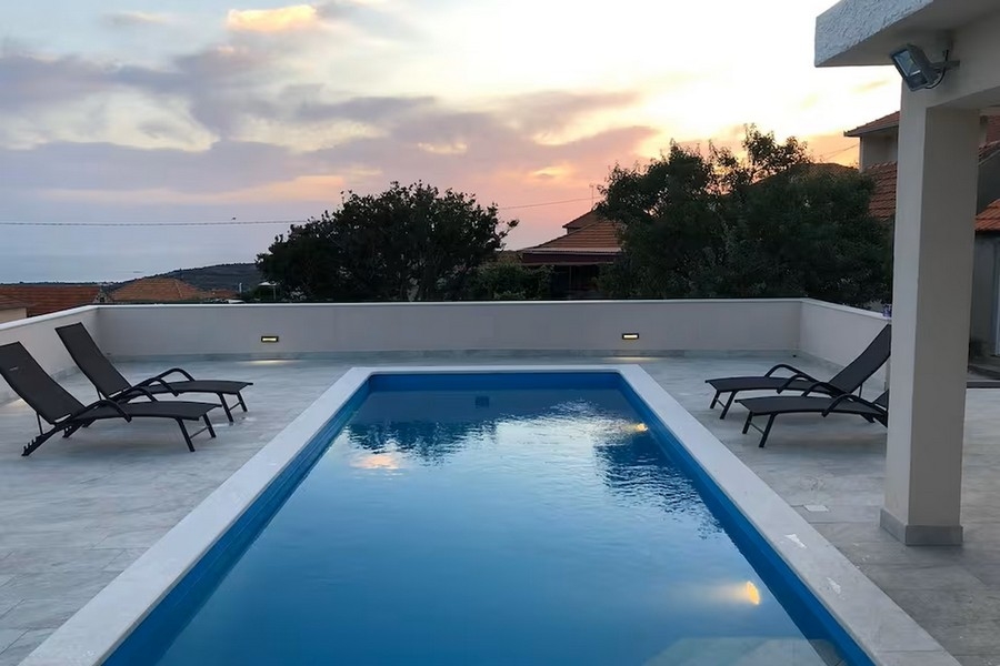 Piscine avec chaises longues et coucher de soleil