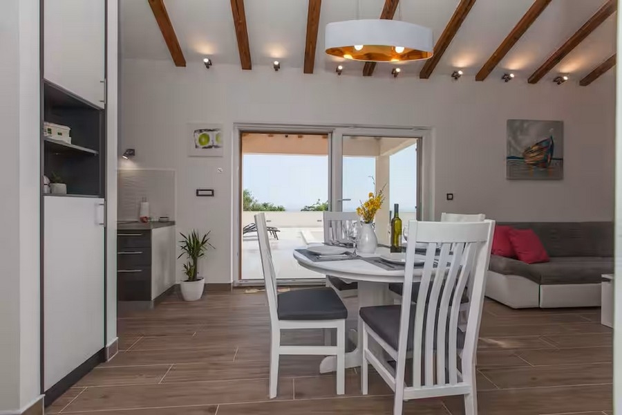 Séjour ouvert avec plafond à poutres en bois et kitchenette