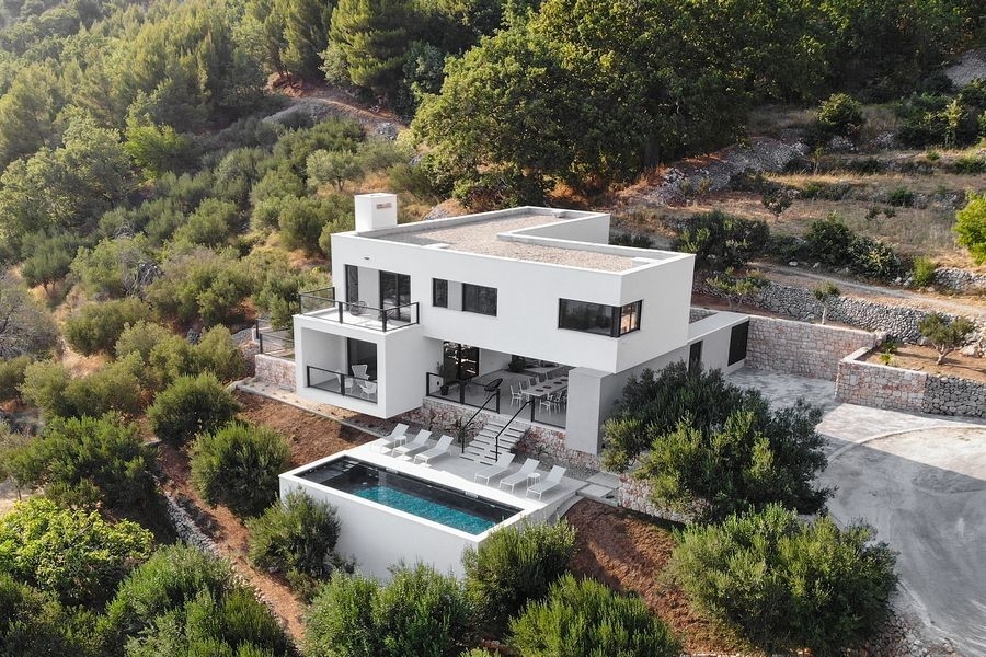 Vue aérienne d'une villa moderne avec piscine à flanc de colline