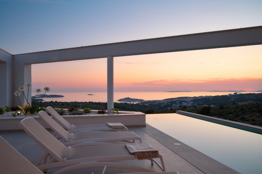 Terrasse avec piscine à débordement et vue mer au coucher du soleil