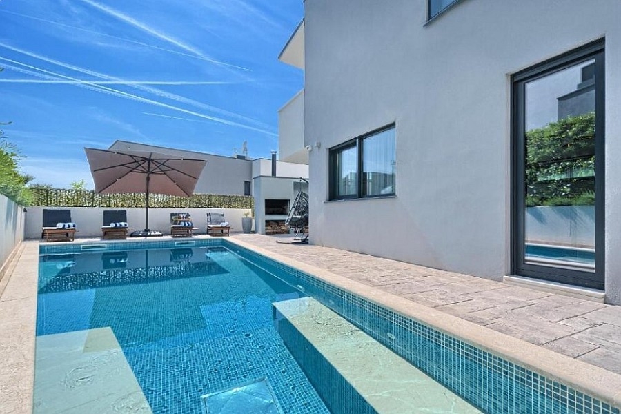 Piscine avec parasol et chaises longues près de la villa