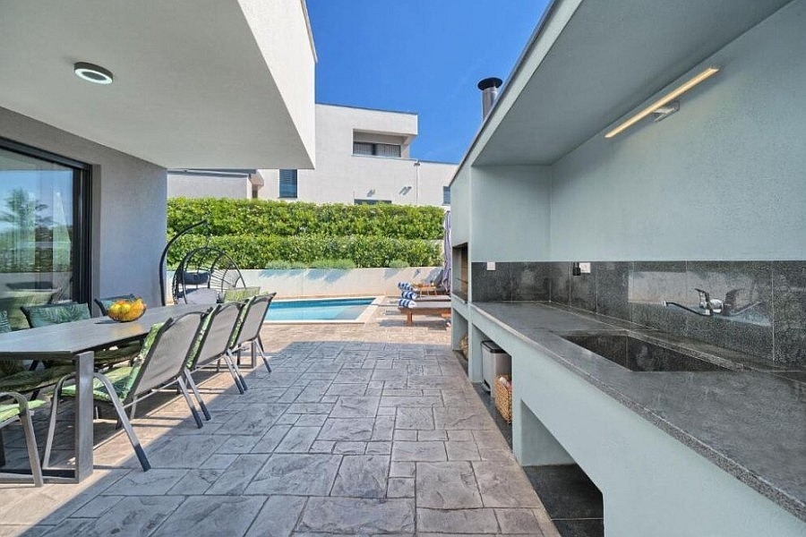 Terrasse couverte avec cuisine d'été au bord de la piscine