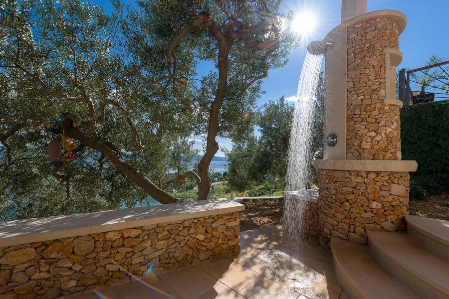 Douche extérieure contre un mur en pierre dans le jardin