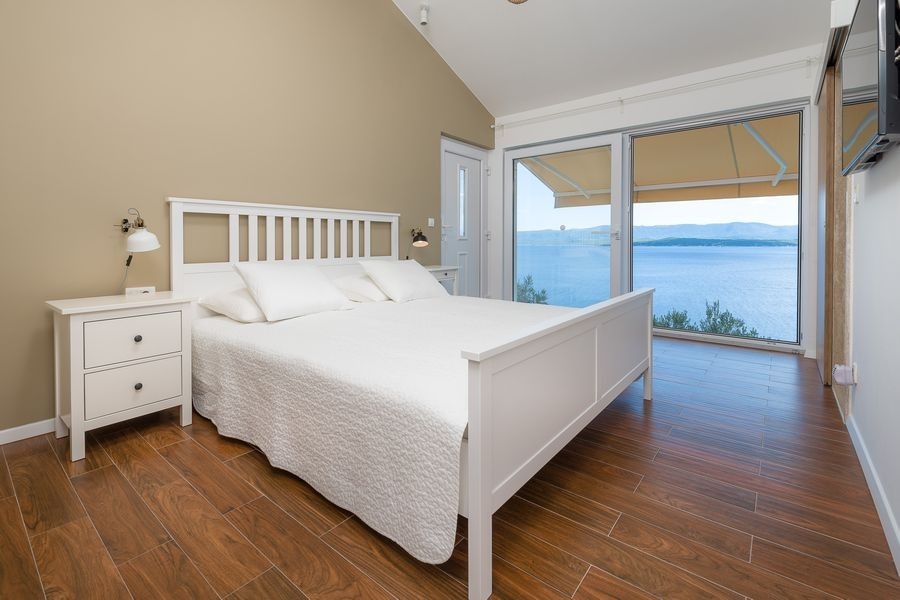 Chambre avec lit double et grandes fenêtres donnant sur la mer