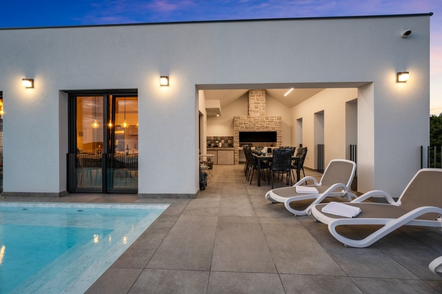 Terrasse couverte avec bains de soleil et piscine le soir