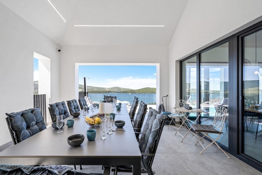 Coin repas clair avec grande baie vitrée et vue mer