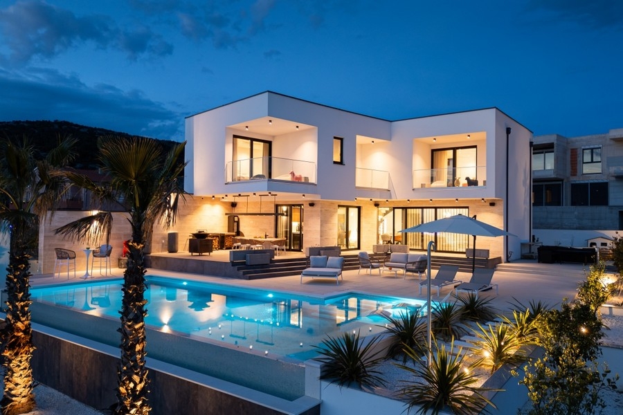 Villa de luxe éclairée avec piscine à débordement au crépuscule