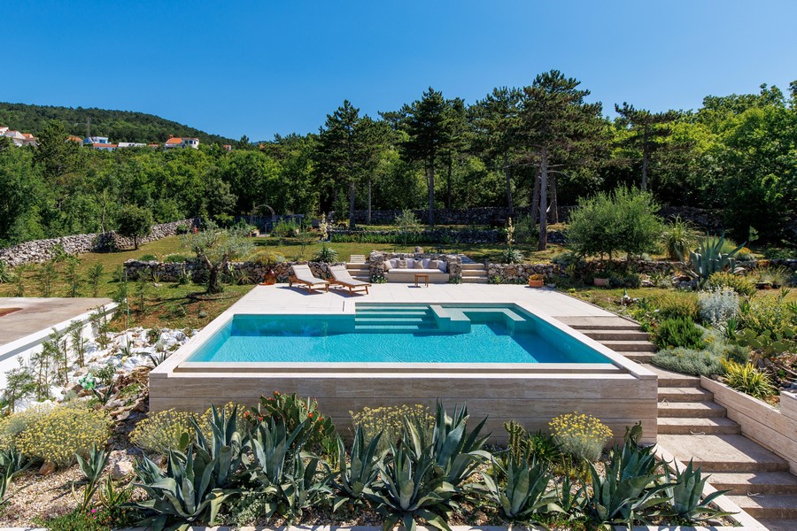 Piscine avec bains de soleil et jardin aménagé