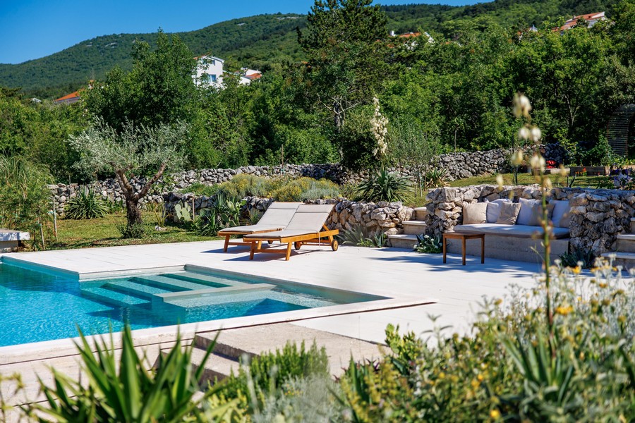 Espace piscine avec bains de soleil et jardin de pierres