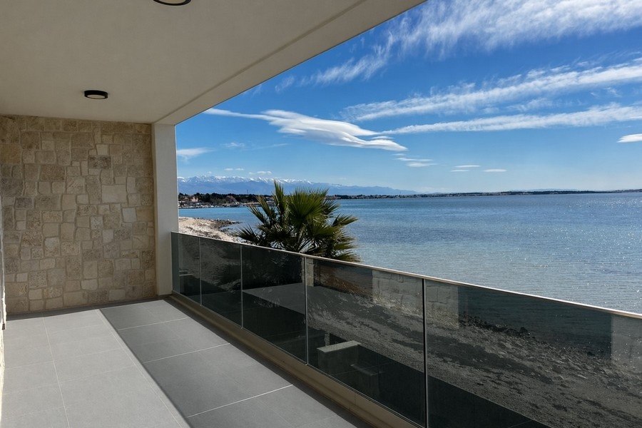 Terrasse couverte avec garde-corps en verre et vue mer