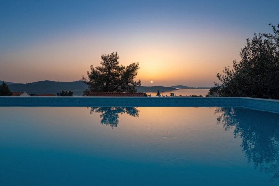 Piscine à débordement au coucher du soleil avec vue panoramique sur la mer