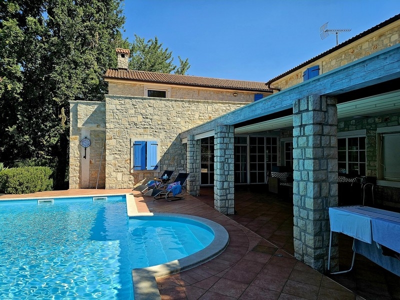 Piscine avec bains de soleil près de la terrasse couverte