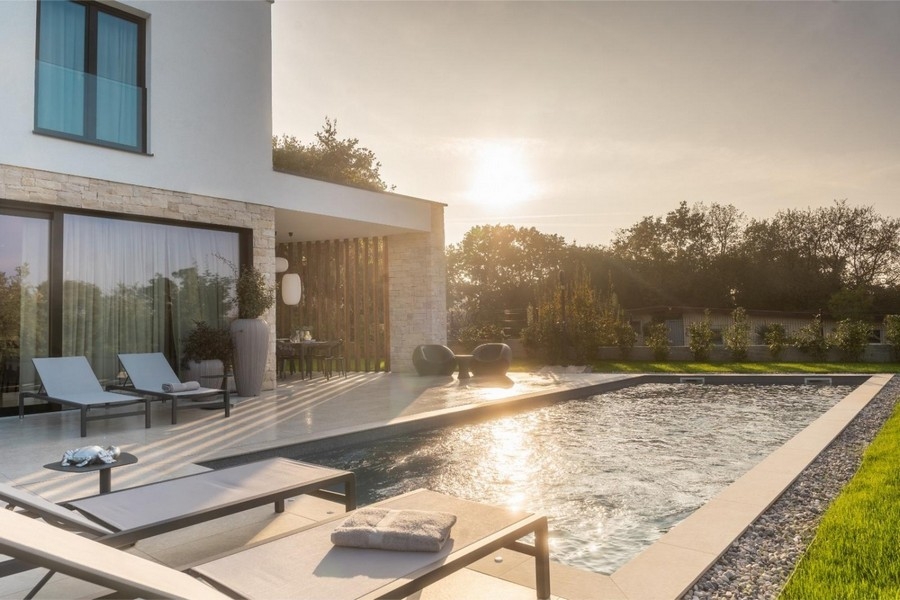 Piscine avec bains de soleil au coucher du soleil