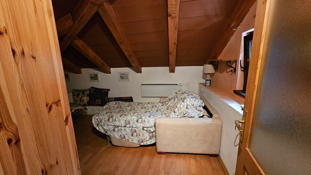 Chambre sous les combles avec lit et poutres en bois
