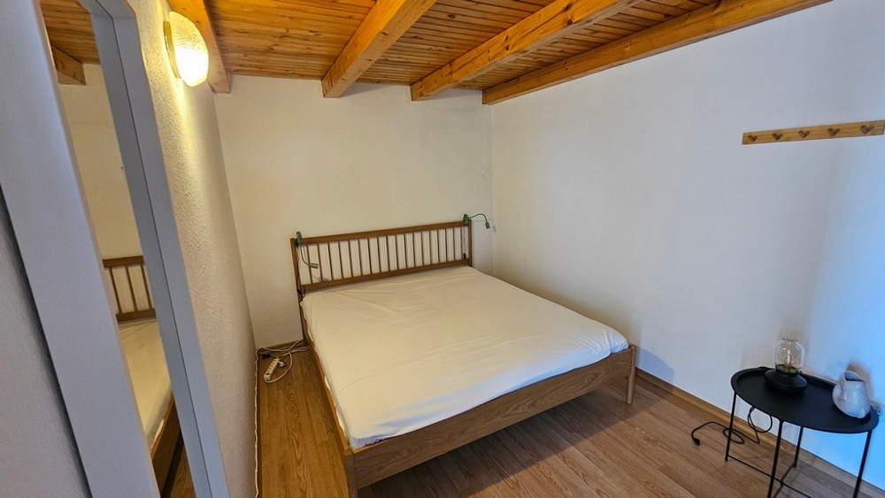 Chambre avec lit double et plafond à poutres en bois