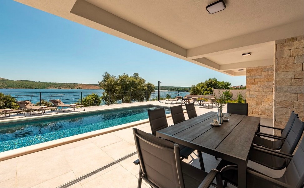Terrasse couverte avec coin salon au bord de la piscine