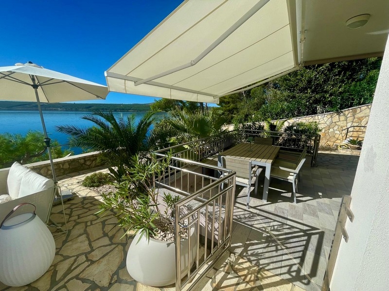 Terrasse couverte avec table à manger et vue mer