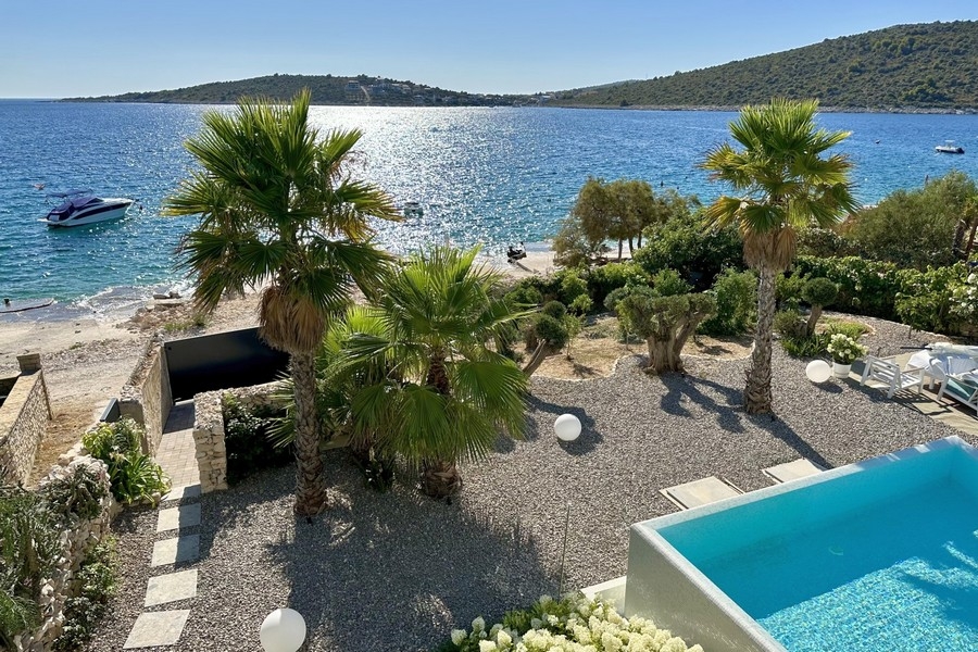 Plage et mer directement devant la villa avec piscine et jardin de palmiers