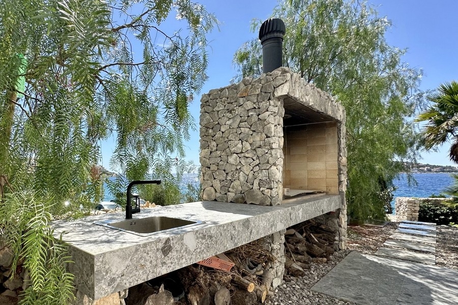 Cheminée extérieure maçonnée avec grill et évier au bord de la mer