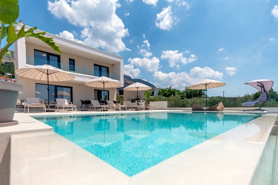 Piscine avec bains de soleil devant la villa