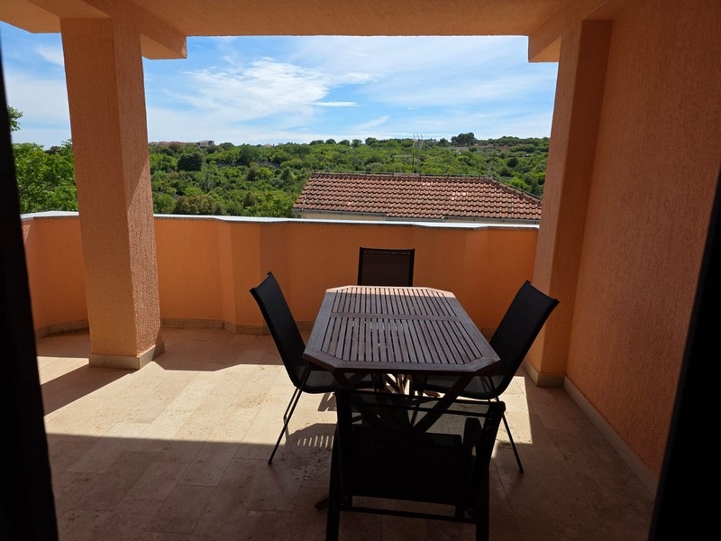 Terrasse couverte avec coin salon et vue sur la verdure