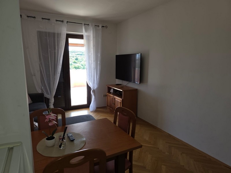 Pièce de vie avec table, télévision et porte donnant sur la terrasse