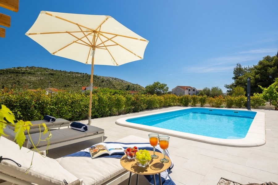 Bain de soleil et table dressée au bord de la piscine