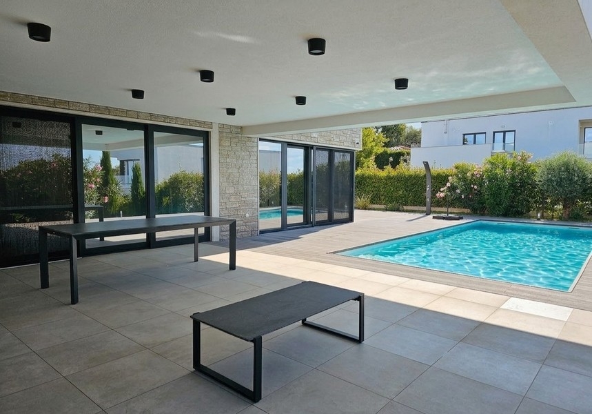 Terrasse couverte avec espace repas au bord de la piscine