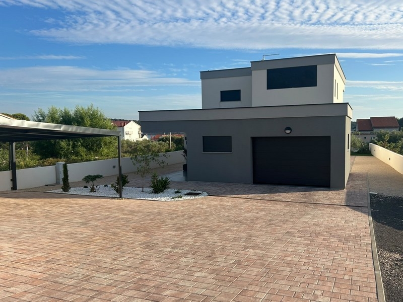 Vue de la maison avec garage et parvis pavé