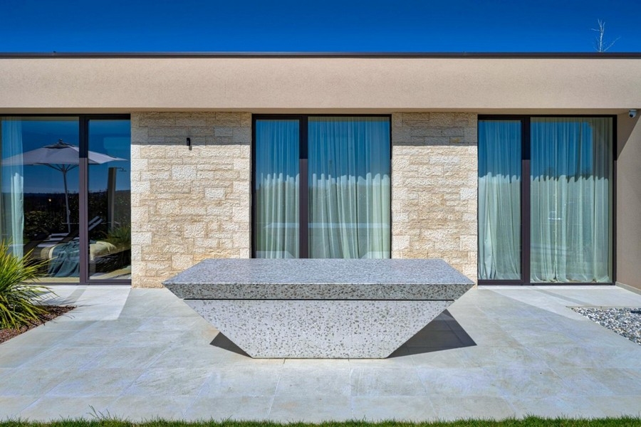 Terrasse avec table en pierre et façade vitrée de la villa