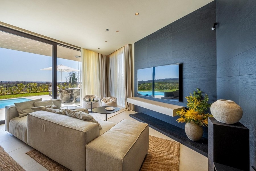 Séjour avec canapé, mur télévision et vue sur la verdure