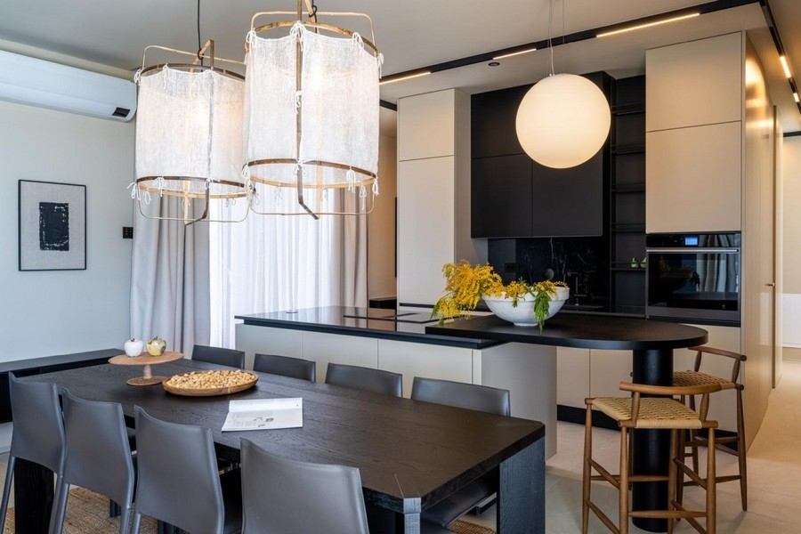 Table à manger avec luminaires design devant la cuisine ouverte