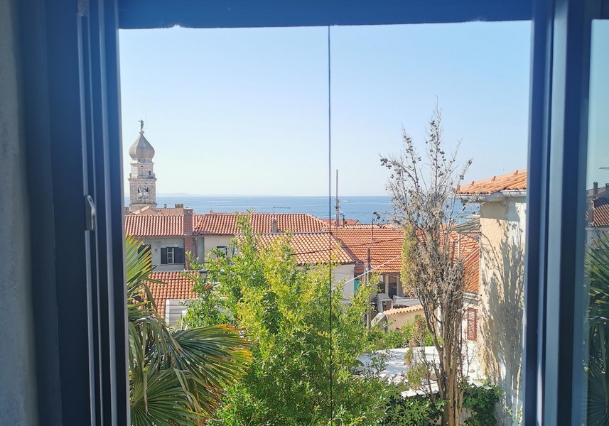 Vue par la fenêtre sur la mer et la vieille ville de Krk avec clocher