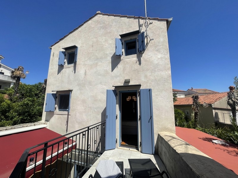 Maison en pierre avec volets bleu clair et toit-terrasse à Krk