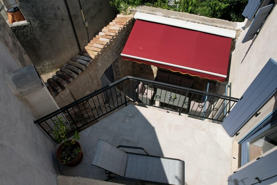 Terrasse avec store rouge et coin salon dans la cour intérieure