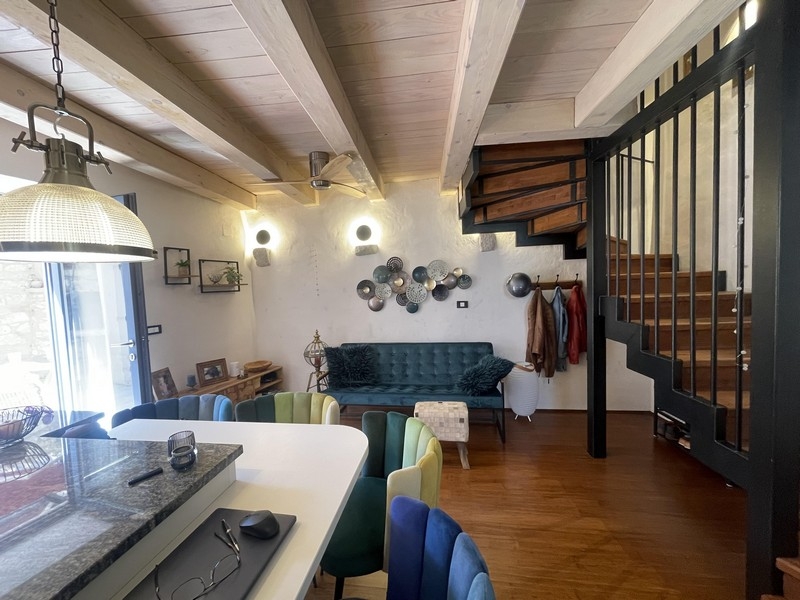 Salon avec canapé, îlot de cuisson et escalier vers l'étage