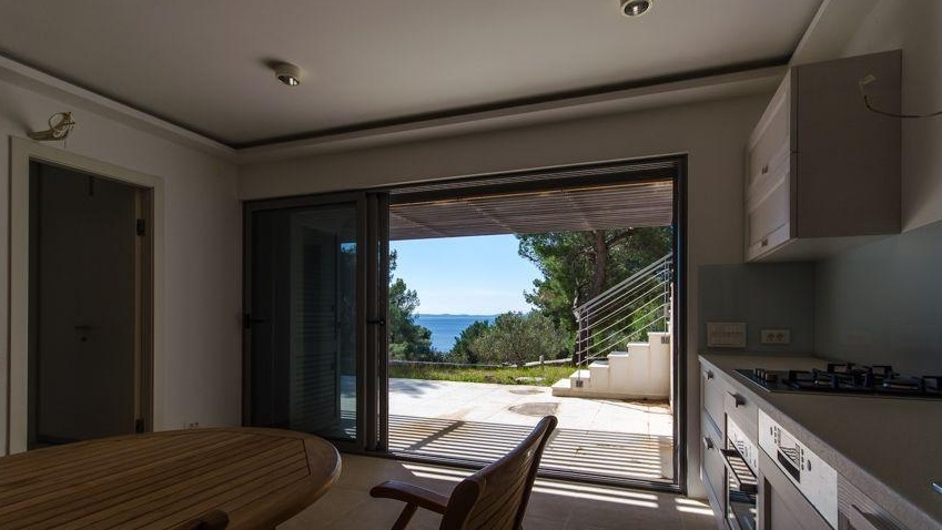 Espace repas avec vue sur la mer à travers la porte de la terrasse