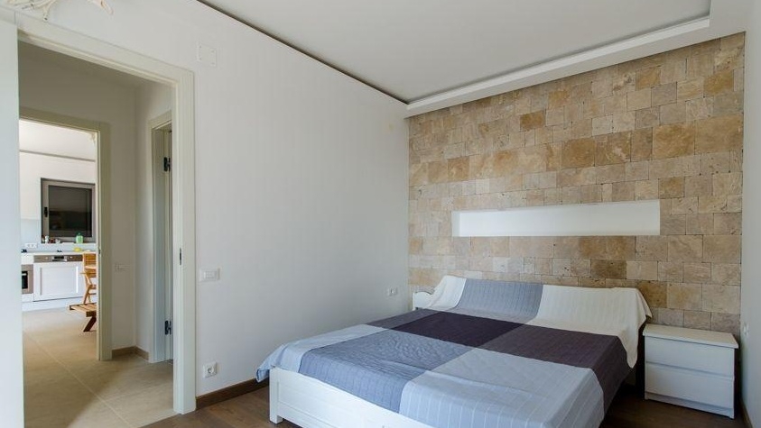 Chambre avec mur en pierre naturelle et lit double