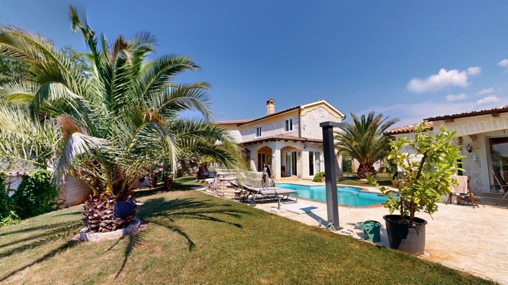 Jardin méditerranéen avec palmiers et piscine devant la maison