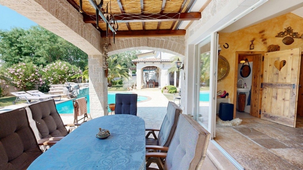 Terrasse couverte de la konoba avec table à manger et vue sur la piscine