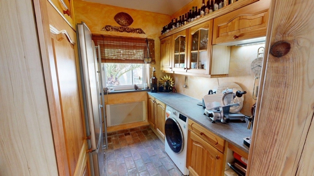 Kitchenette avec placards en bois et lave-linge