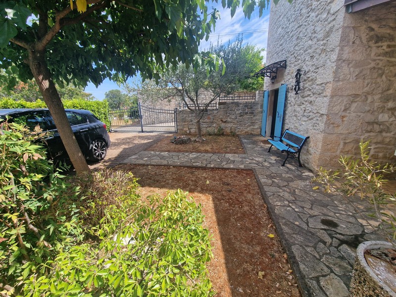 Jardin avec place de stationnement devant la maison en pierre